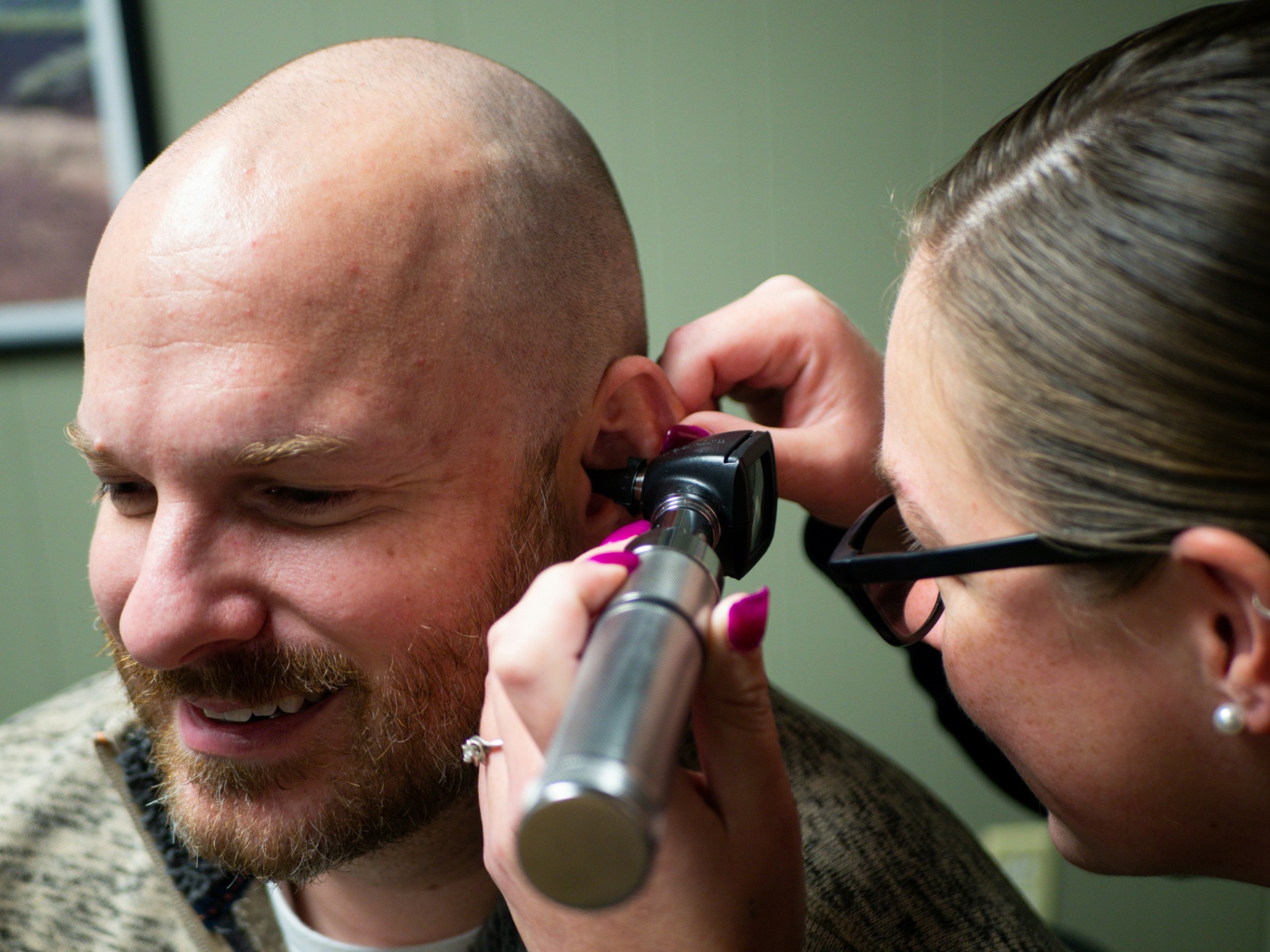 An audiologist examining a patient's ear with an otoscope before a hearing assessment