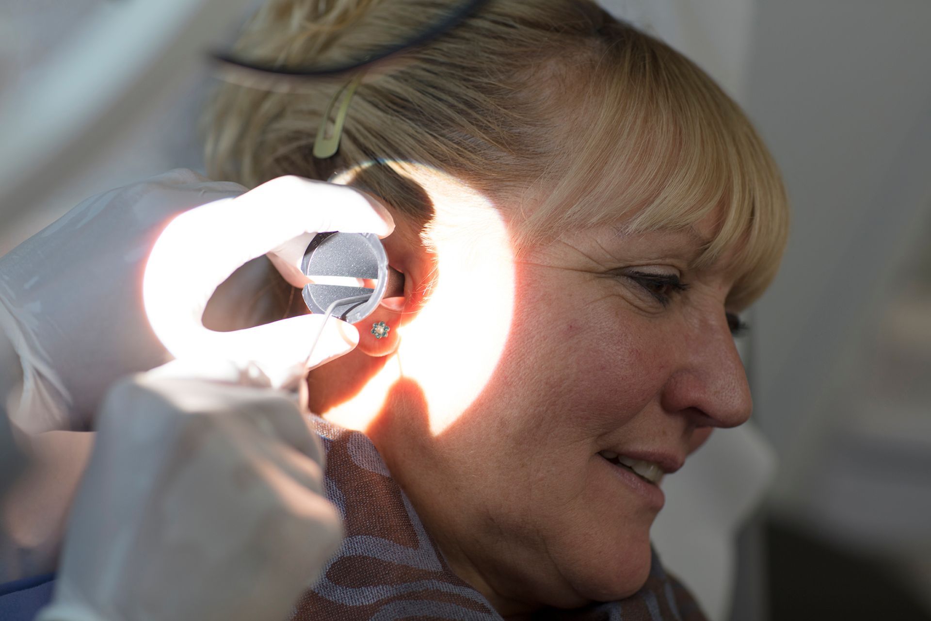 An audiologist using a microsuction handpiece and magnifying loupe to clear ear wax at our Kenfig Hill, Bridgend clinic