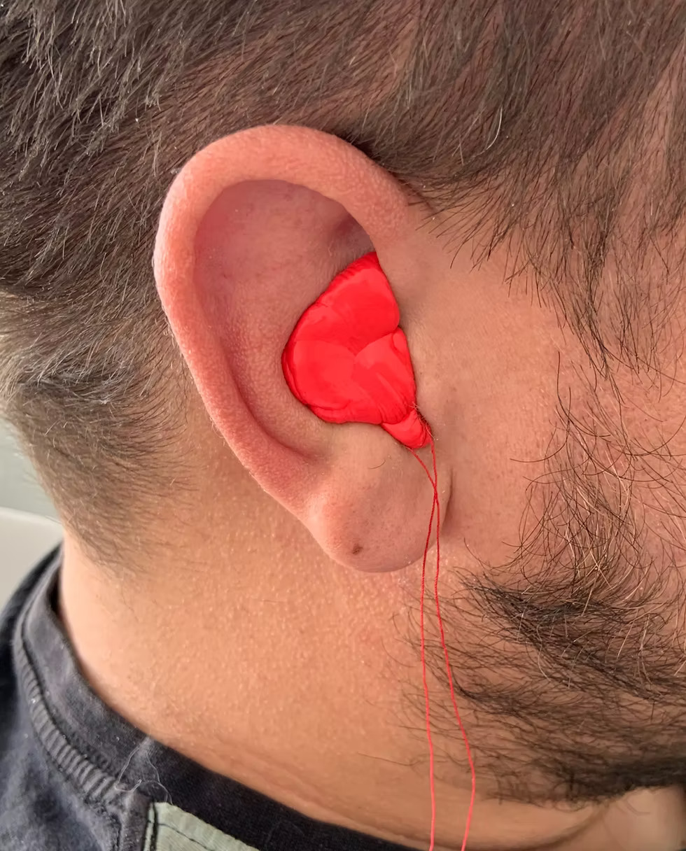 An audiologist taking an ear impression with bright pink moulding material