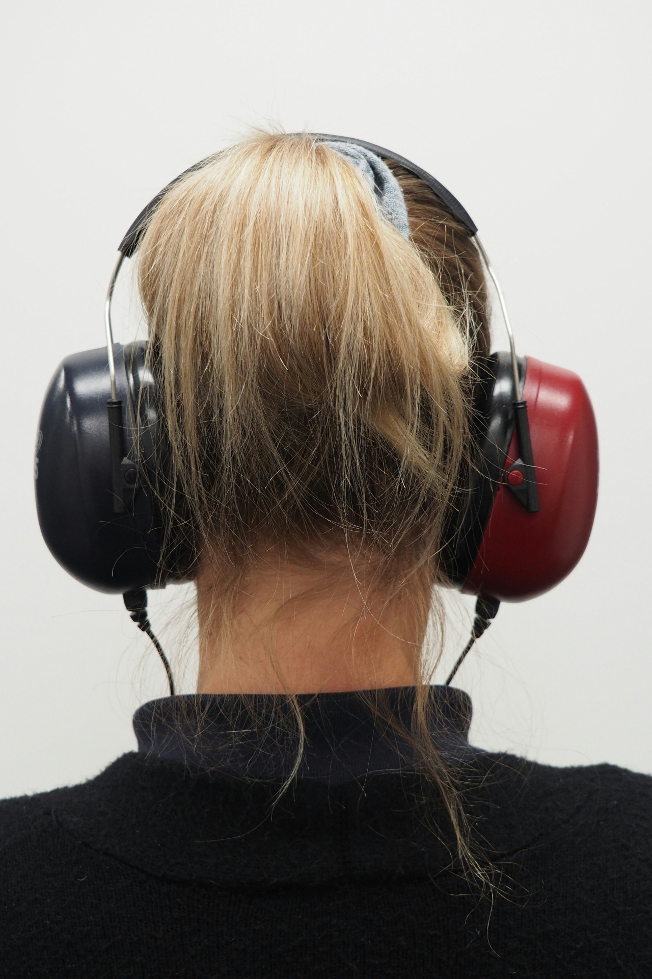 A patient seated in a sound-treated booth wearing over-ear audiometric headphones for a hearing test