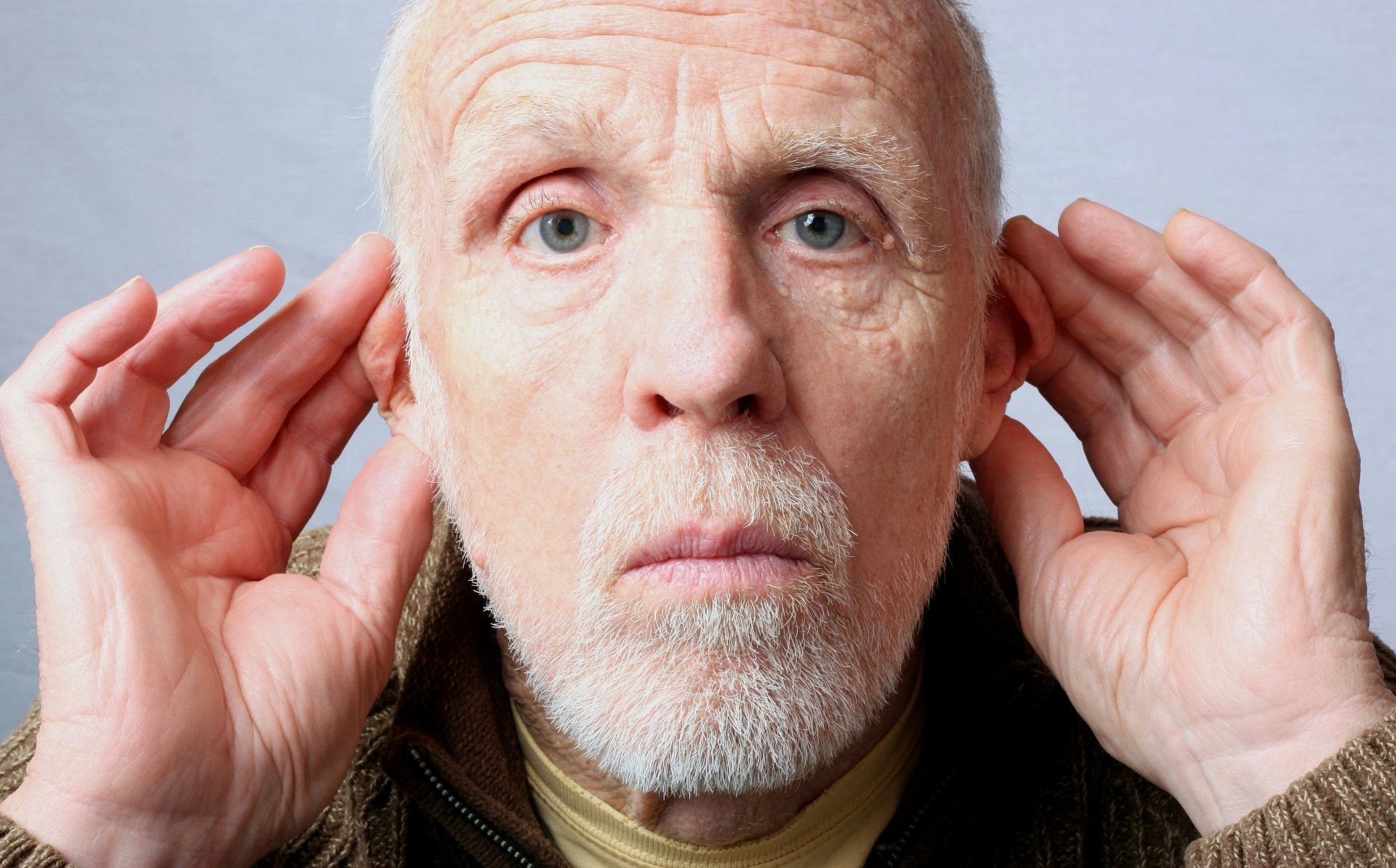 A woman leaning in and cupping her ear to follow a conversation she cannot hear clearly
