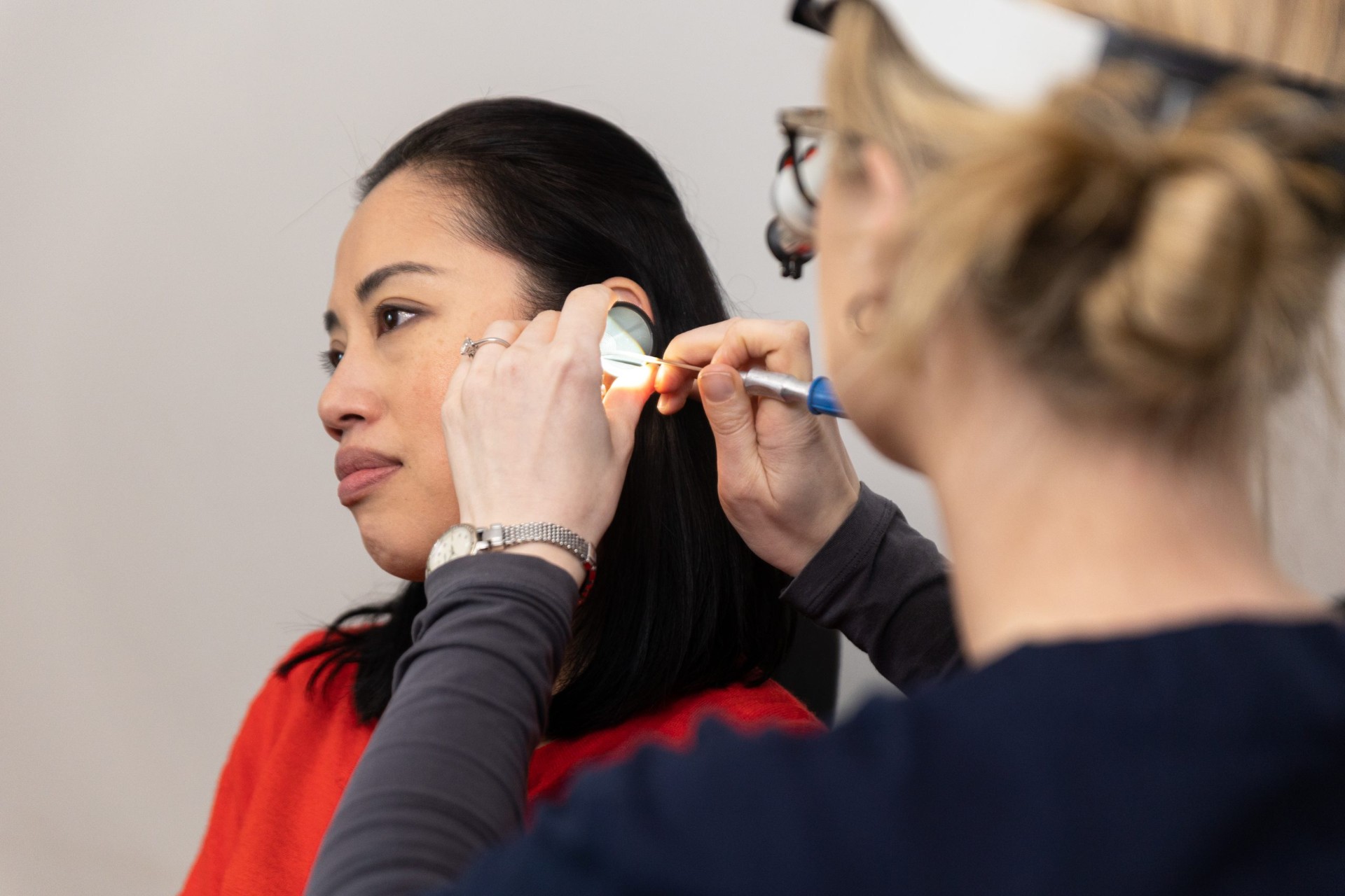 An audiologist examining a patient's ear canal with a handheld otoscope